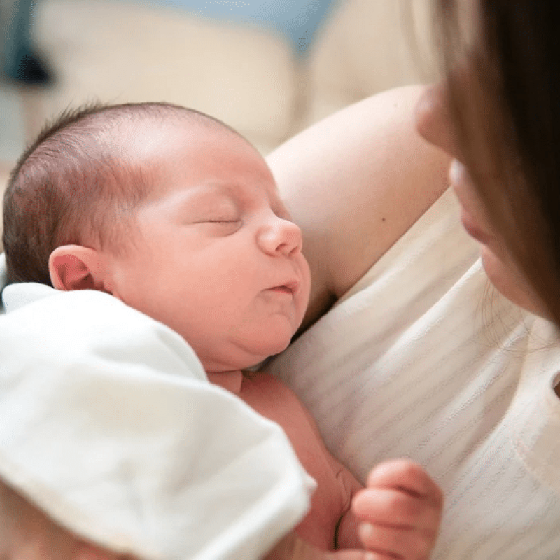 Bébé endormi dans les bras de sa mère